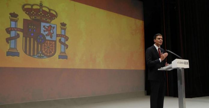 Una bandera de Espana en una pantalla gigante fue el marco de buena parte del discurso de Sánchez