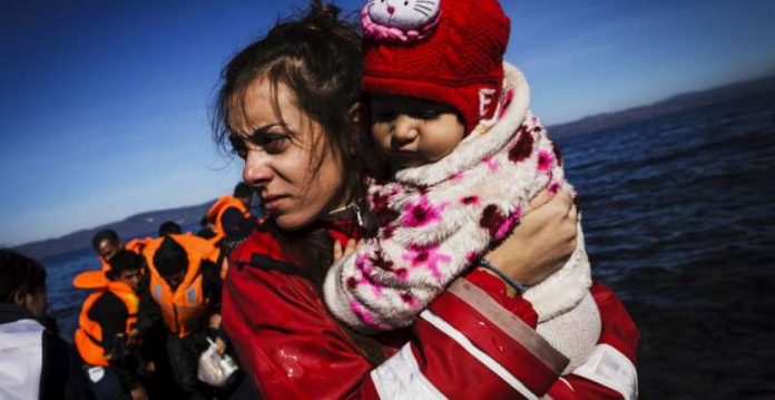 Una voluntaria sostiene en brazos a una peligrosa terrorista en la isla de Lesbos poco después de embarcar con su familia en un bote neumático